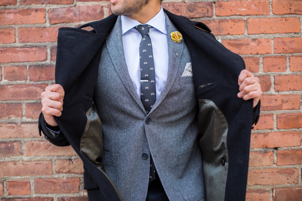 grey suit with bicycle tie and black top coat