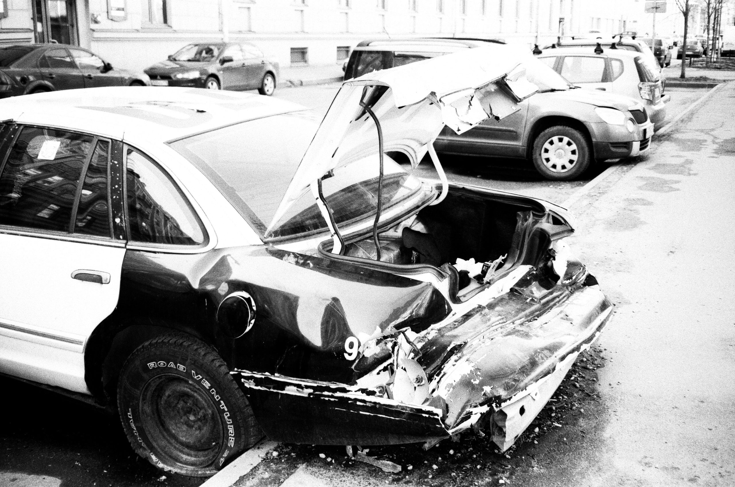 grayscale-photo-of-wrecked-car-parked-outside-1230677