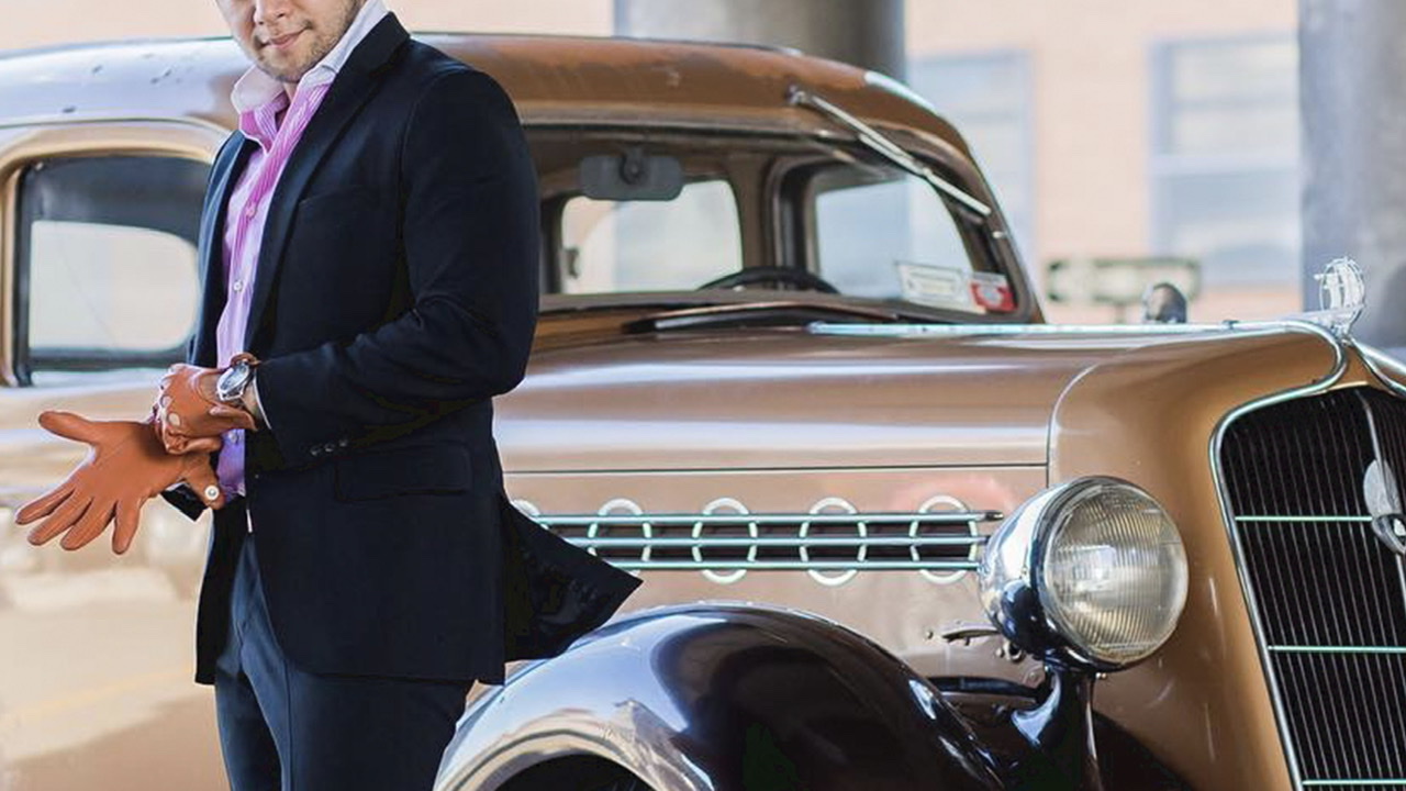 Man in a suit with gloves next to a vintage car - dandy in the bronx