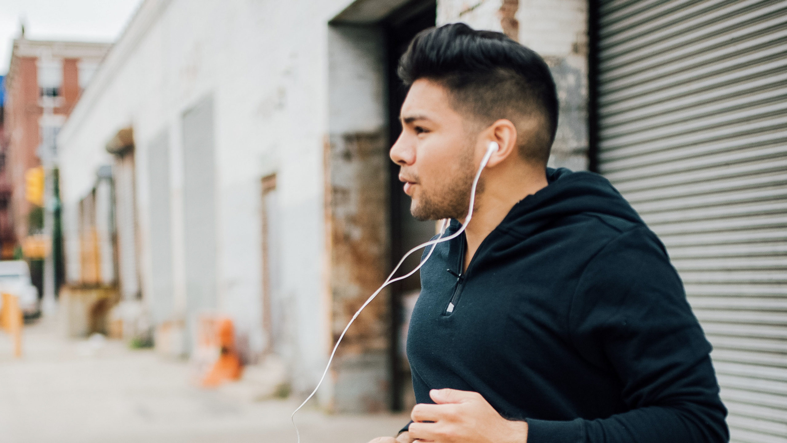 Latino man running with an earphones - dandy in the bronx - fitness man - black hoodie -