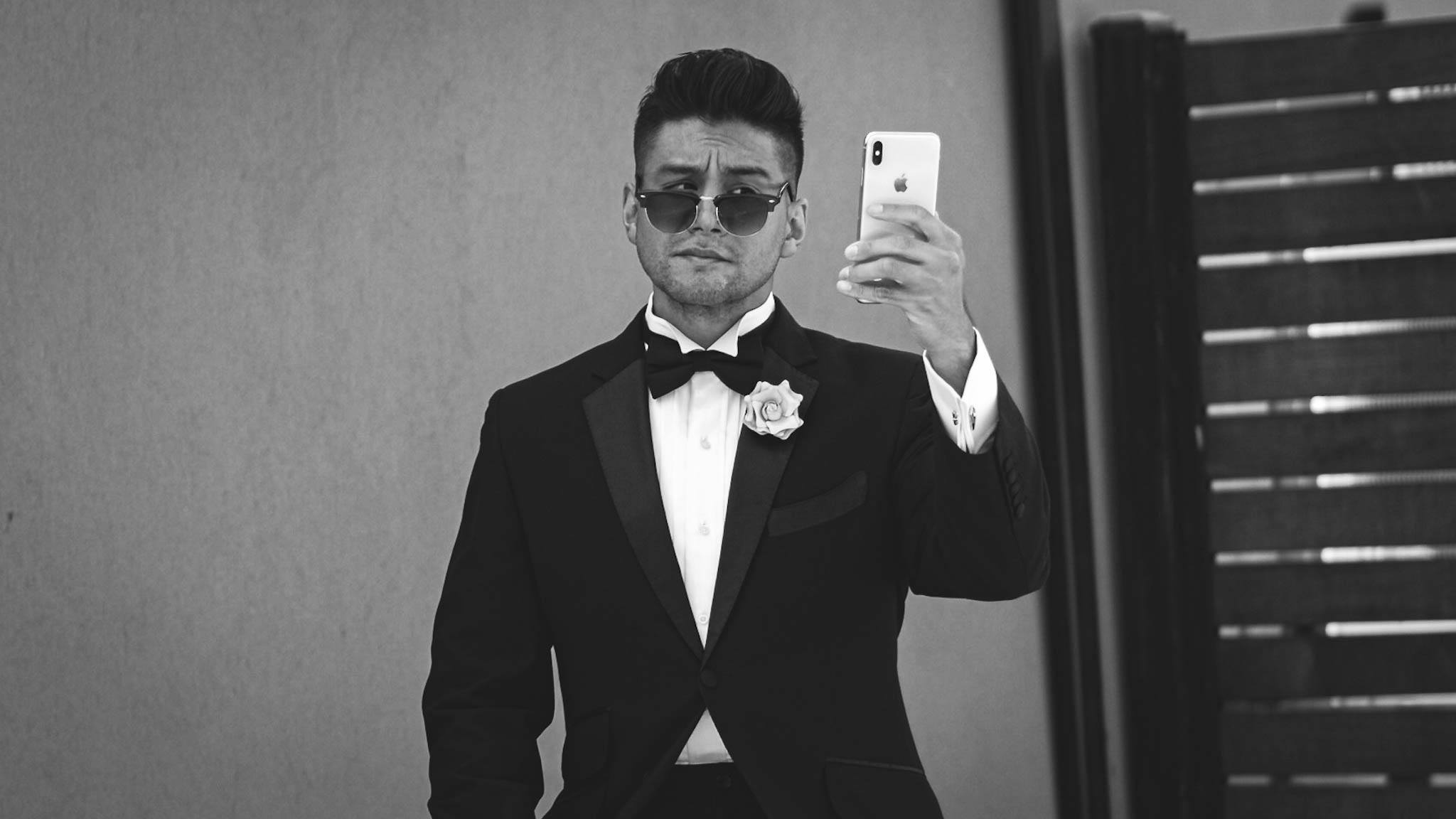 Black and white photo - man in tuxedo holding a phone - man in sunglasses - man in tuxedo with sunglasses - man in bow tie - black bow tie - dandy in the Bronx