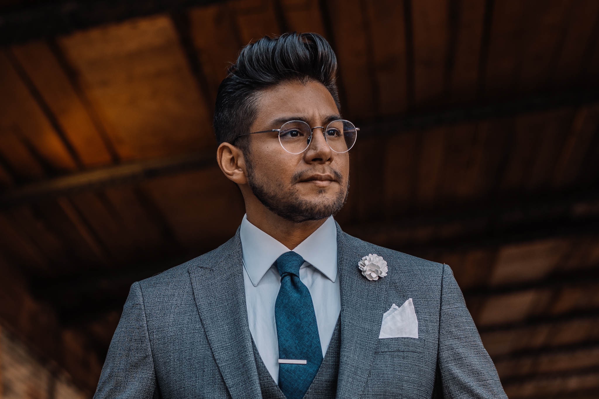 latino man in three piece suit wearing glasses. Grey three piece suit - sayki suit - round glasses - blue tie - dandy in the bronx