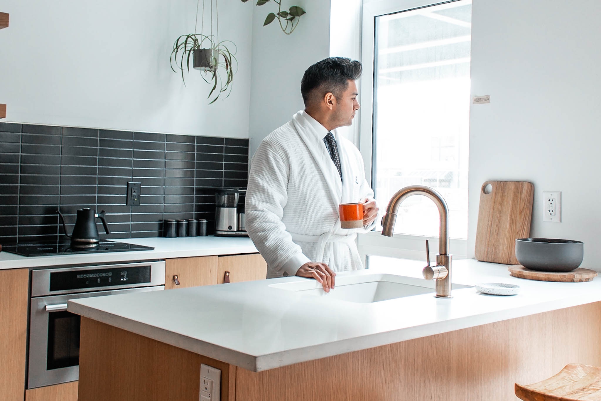 With with shirt and tie and robe handing over a sink while holding a coffee