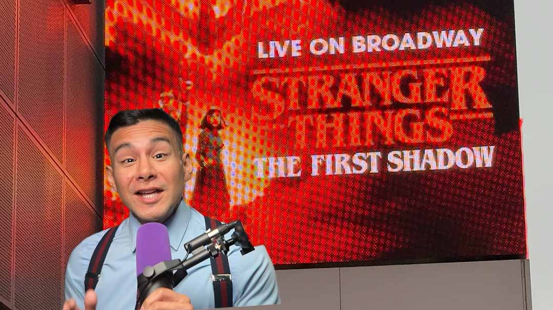 Diego Leon of Dandy In The Bronx speaking into a microphone with a digital billboard for Stranger Things The First Shadow on Broadway in the background.