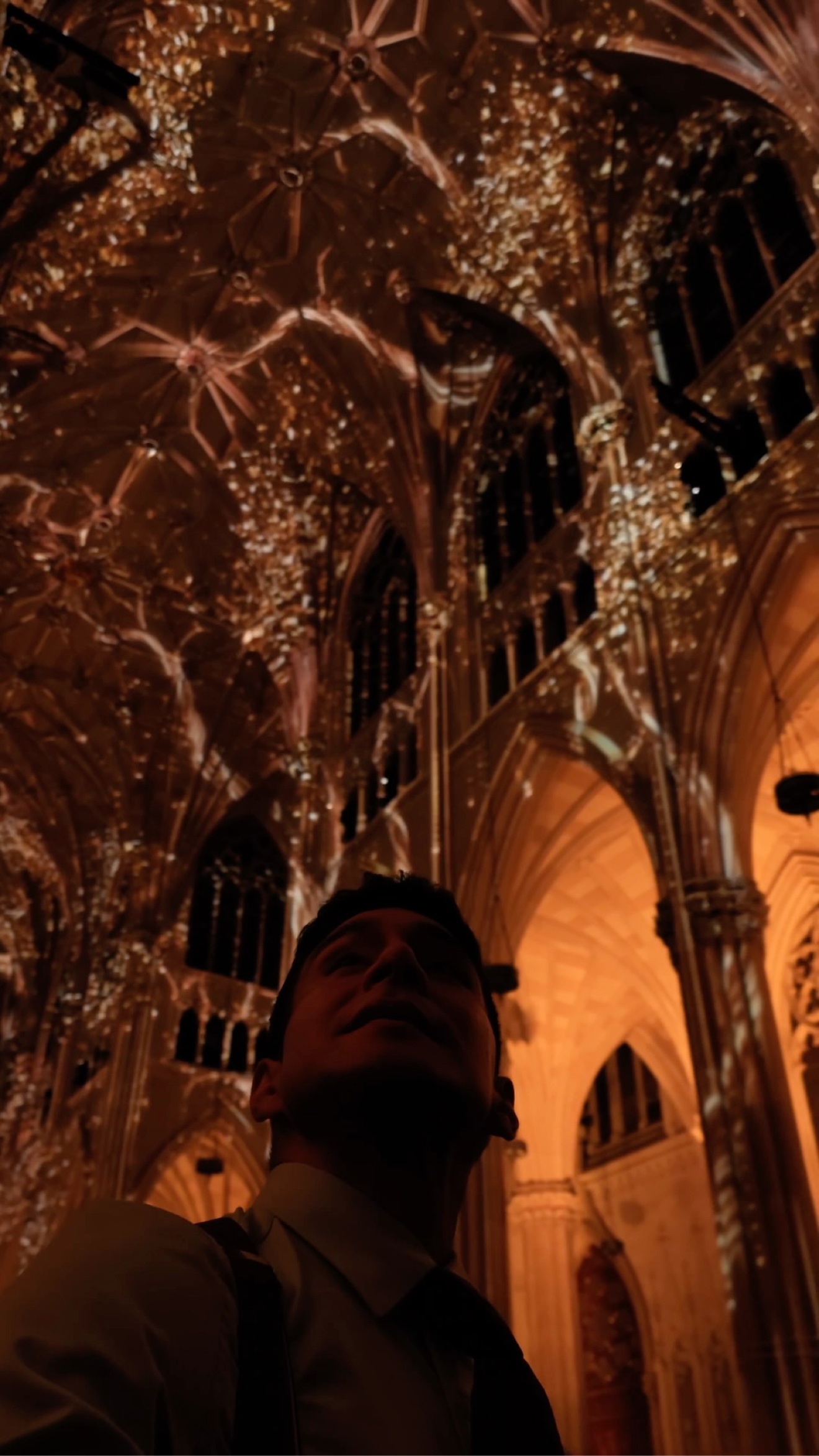 Diego Leon looking up at the golden video-mapped ceiling during LUMINISCENCE at St. Patrick's Cathedral in New York City