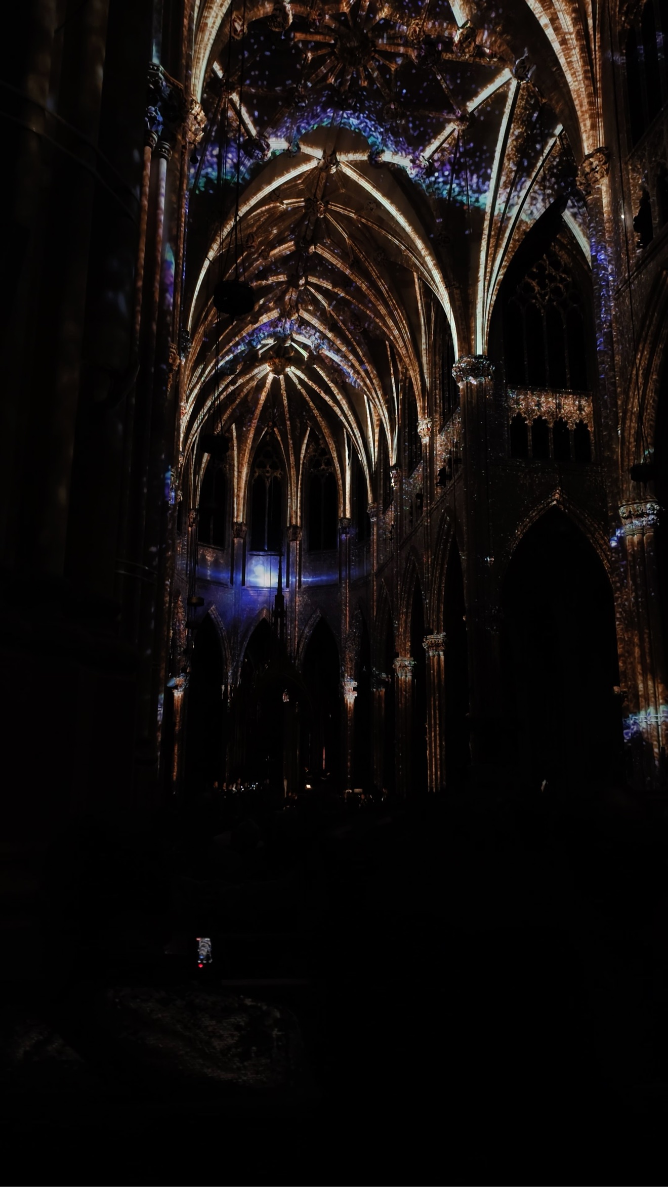 Wide view of the nave of St. Patrick's Cathedral lit with purple and gold LUMINISCENCE projections