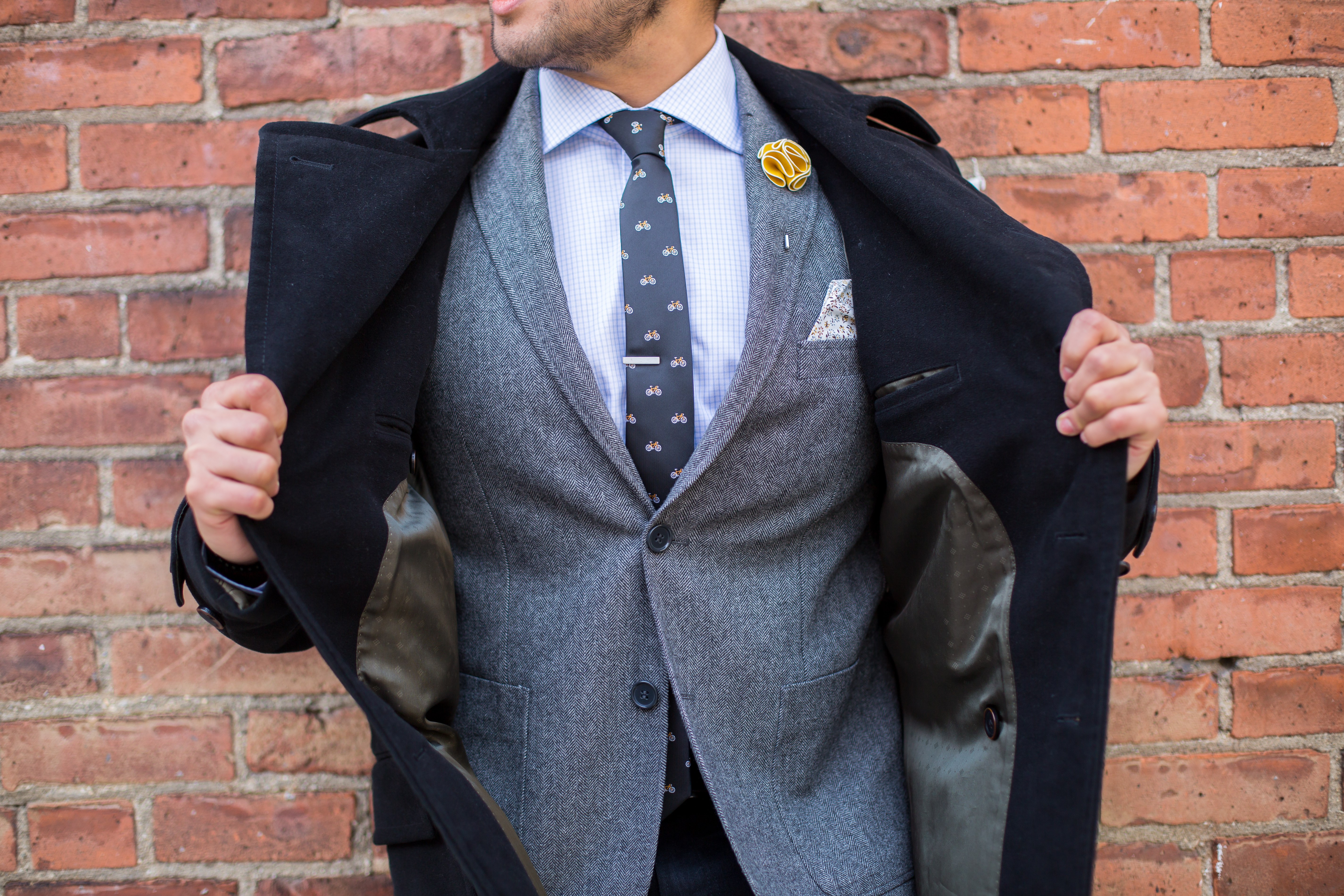 grey suit with bicycle tie and black top coat